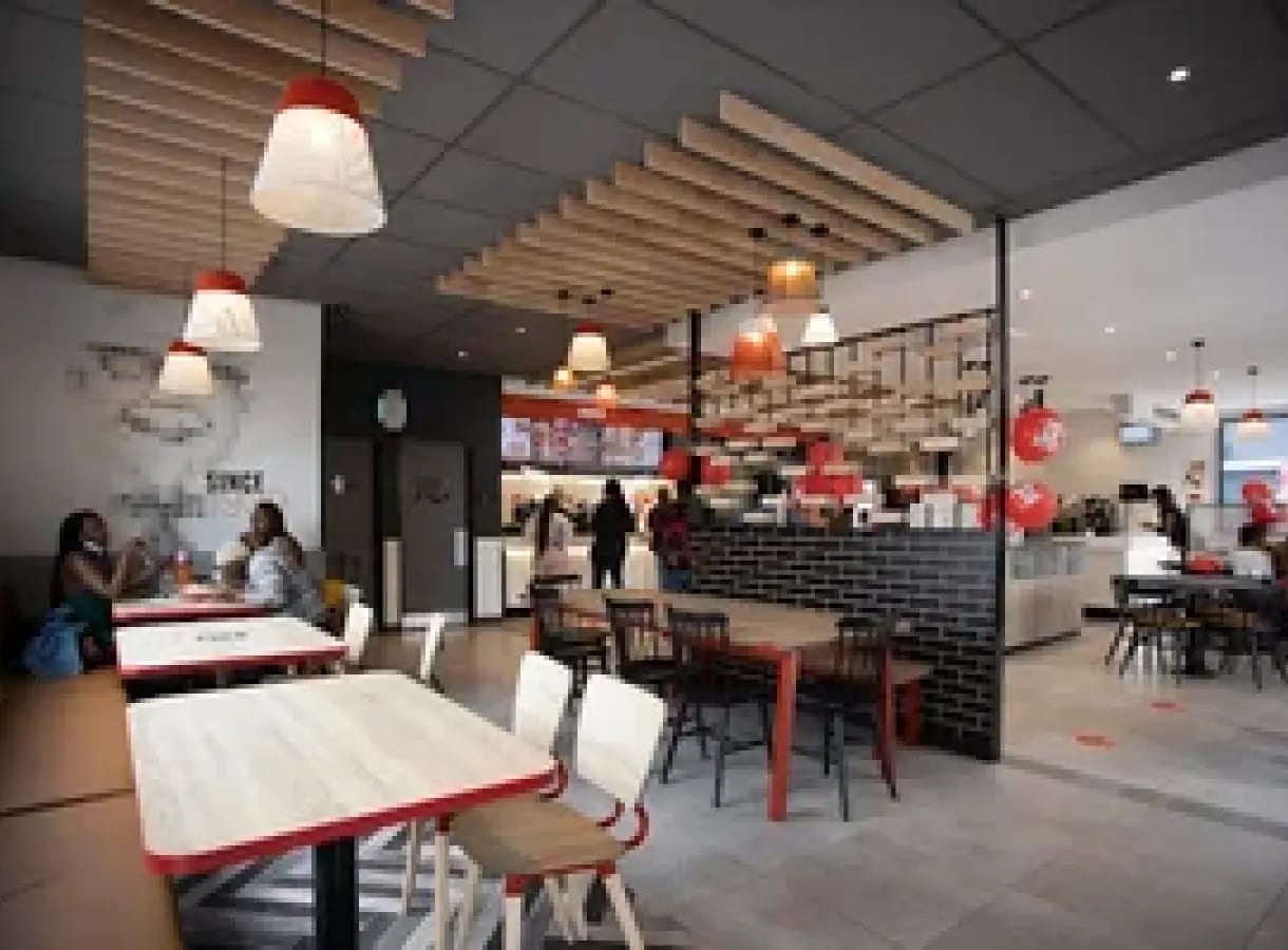 KFC Albimix crew behind the counter of a Gauteng store, in uniform, mid-service — the 351 people across eight stores this story is about