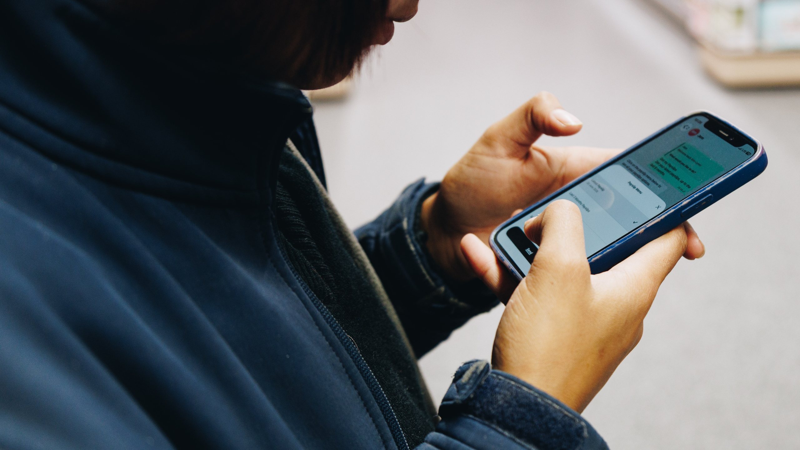 A worker in a navy fleece tapping out a reply in a Jem WhatsApp conversation on their phone