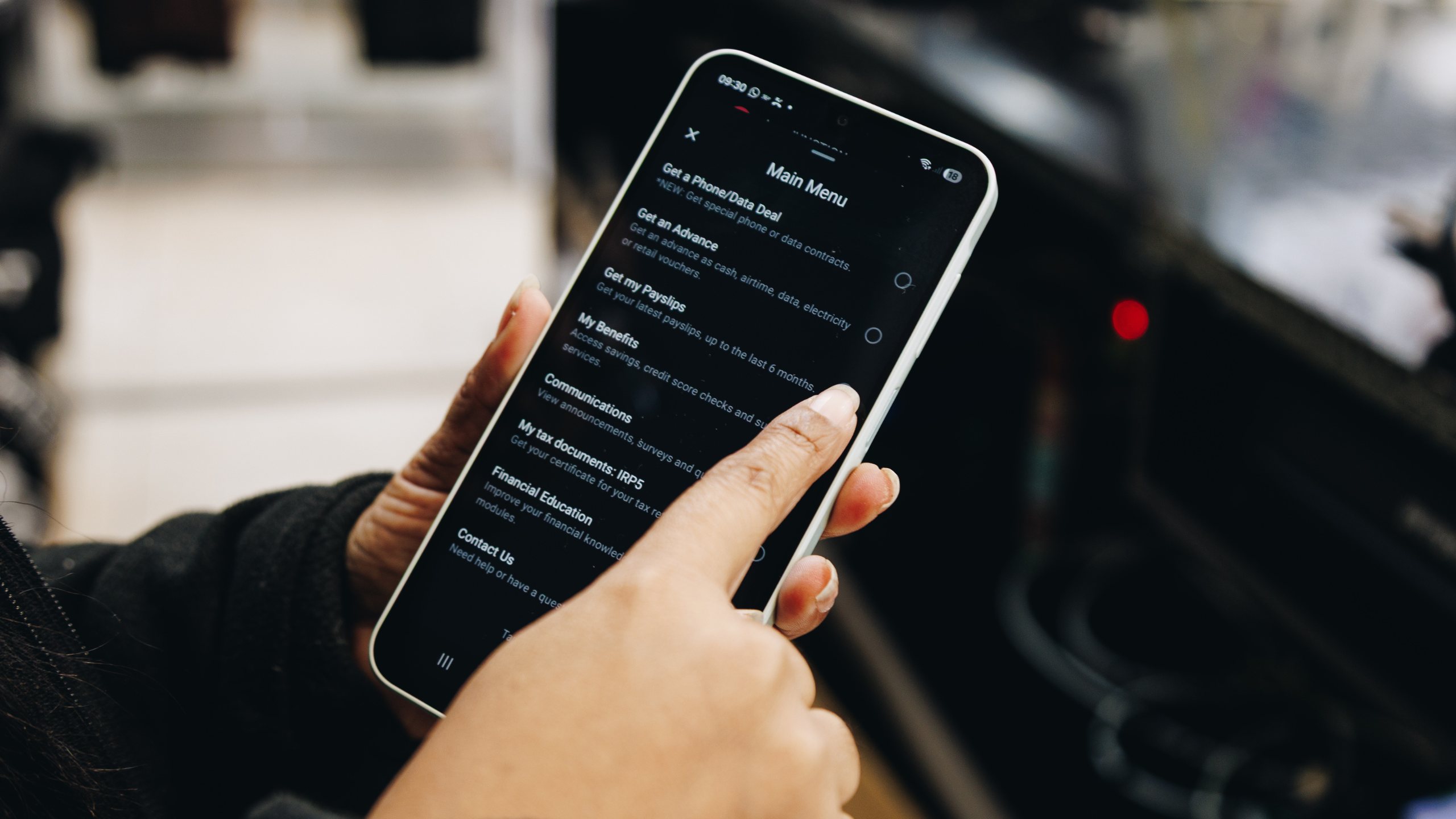 A hand tapping the Jem main menu on a phone, showing options for payslips, advances, benefits and tax documents